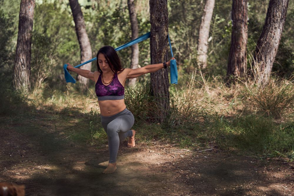 Fit woman squatting and outstretching arms with resistance