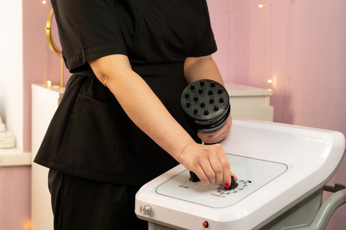 A therapist selecting intensity on a body sculpting device control panel