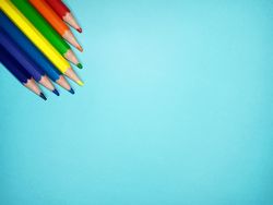 Seven color pencils on a light blue background provide space for text or wording