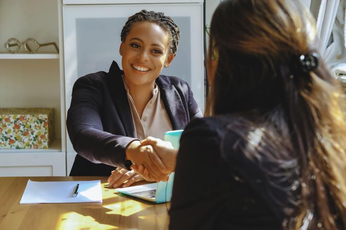 Confident business owner shaking hands after a meeting with woman in bright office