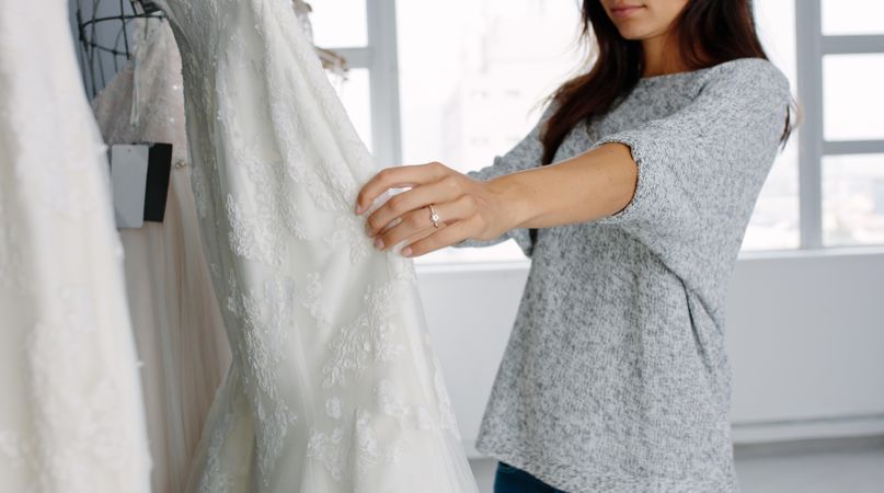 Young woman looking at bridal gowns on display in boutique