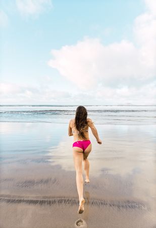 Woman in swimwear running near sea