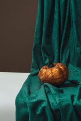 Retro still life with glitter pumpkin and green curtain