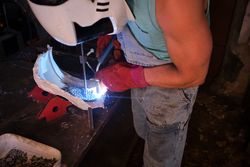 Unrecognizable worker welding metal in workshop