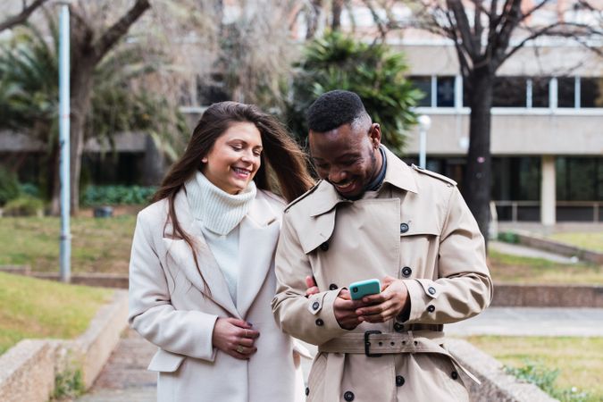 Joyful multiethnic couple using smartphone in park