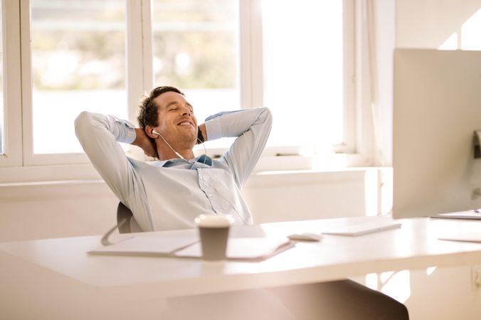 Smiling businessman resting in office chair at home office