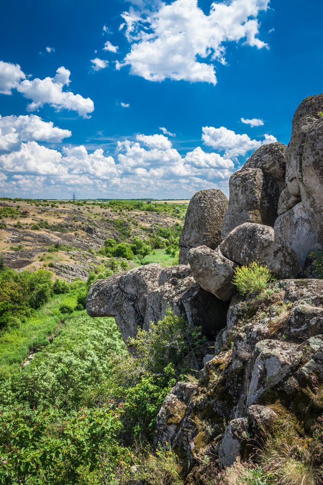 Gray rock formation on green grass field under cloudy sky