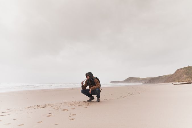 Man smoking pipe on sand shore near water