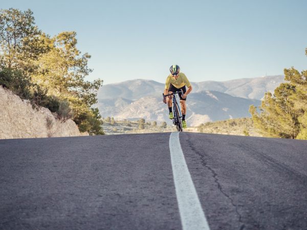 healthy man riding a bicycle on a mountain road in a sunny day