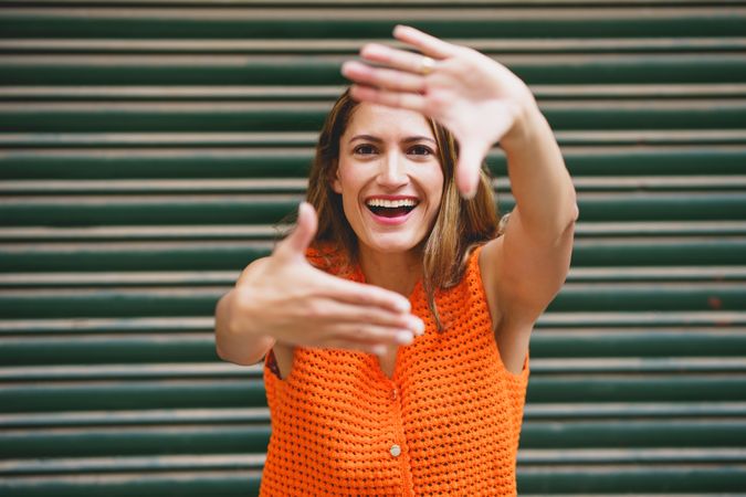 Cheerful Latina woman smiling while shaping frame with her fingers