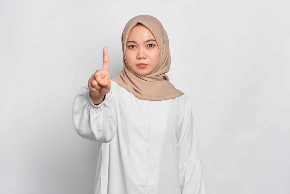 Stern Asian female in headscarf with finger up
