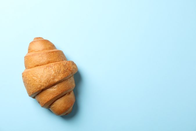 Freshly baked croissant on blue background, top view, copy space