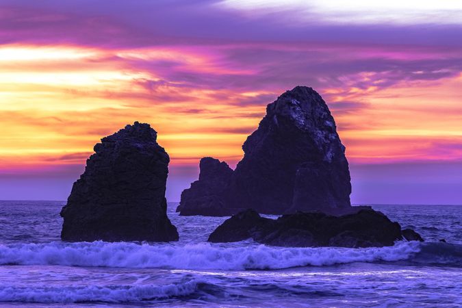 Waves cresting on rocks in the Pacific Ocean during colorful dusk