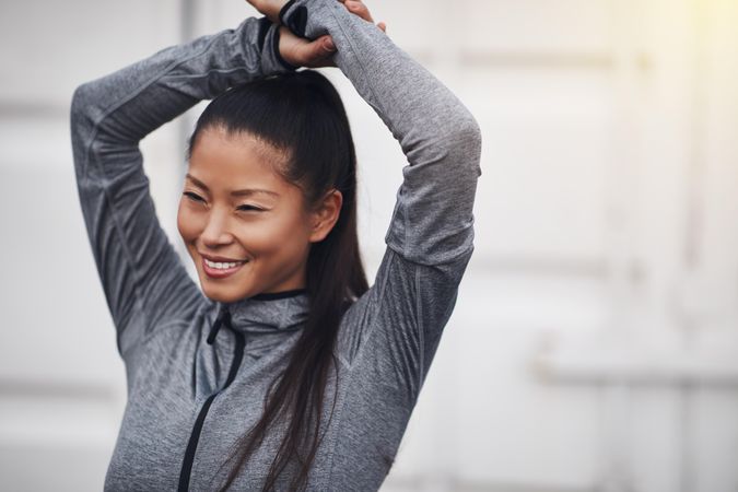 Happy woman in workout gear with arms above head