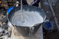 Worker mixing plaster in bucket