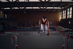 Young male gymnast doing exercises on the parallel apparatus.