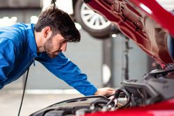 White man working in auto repair shop on red car