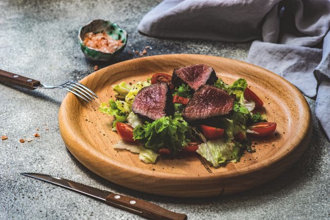 Steak salad with fresh lettuce on wooden plate