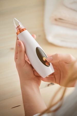 Unrecognizable woman holding vacuum acne cleaner