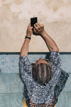 Back of man using smartphone in swimming pool