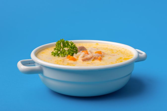 Chicken soup bowl close-up, isolated on a blue background