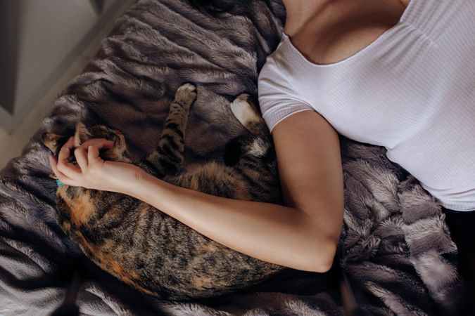 Young woman stroking cat on bed
