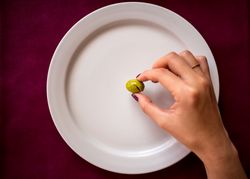 Faceless woman eating olive in restaurant