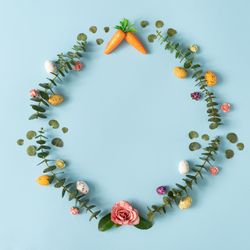 Colorful flowers, carrots, and Easter eggs on blue background