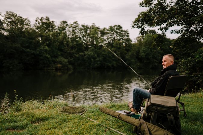 Happy man sitting and fishing by river