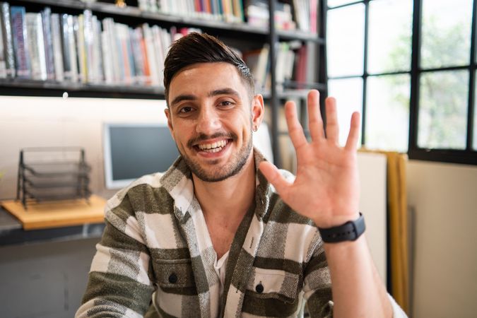 Male creative smiling and waving in relaxed modern office