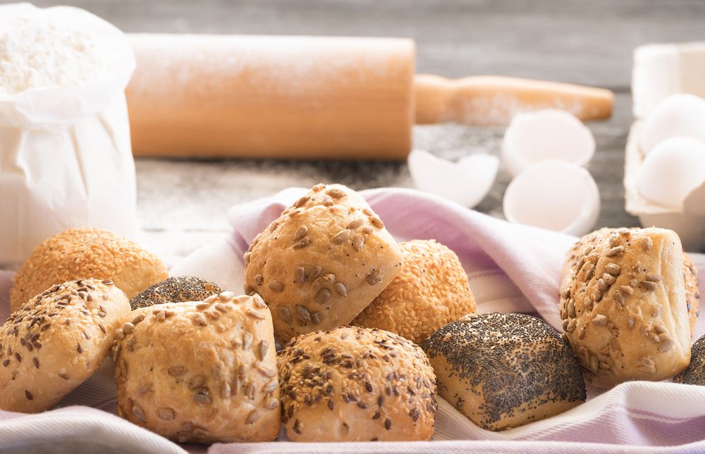 Homemade bread rolls with seeds with rolling pin in background