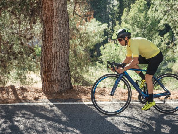 healthy man riding a bicycle on a mountain road in a sunny day