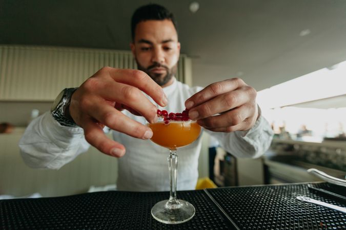 Cheerful man preparing a cocktail in a bar.