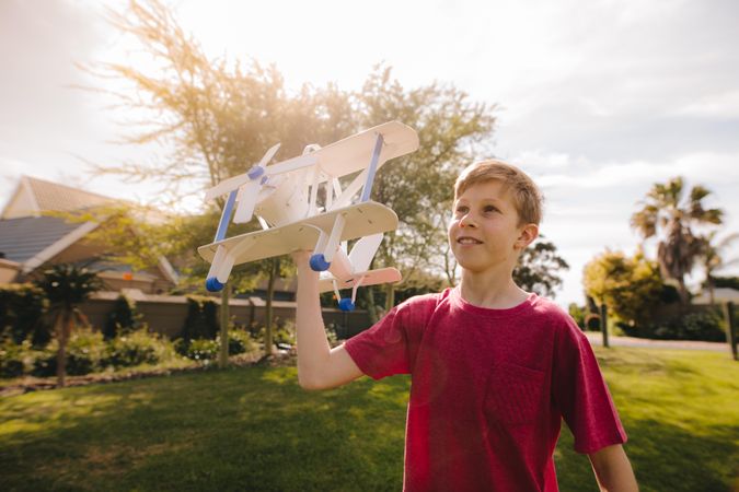 Kid playing with a toy airplane on a sunny day