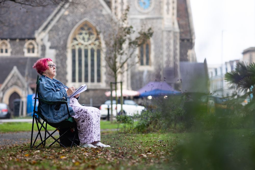 Side view of woman sitting outside church and drawing