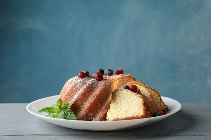 Cake with powder sugar and berries on wooden background, space for text