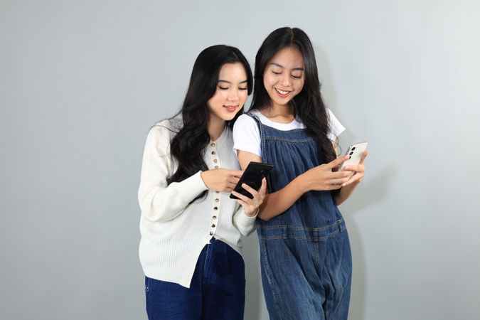 Two Asian Young Woman Holding Mobile Phone, Happy Bestfriend Interacting.