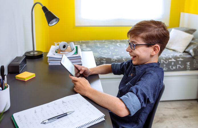 Happy preteen doing homework with a tablet