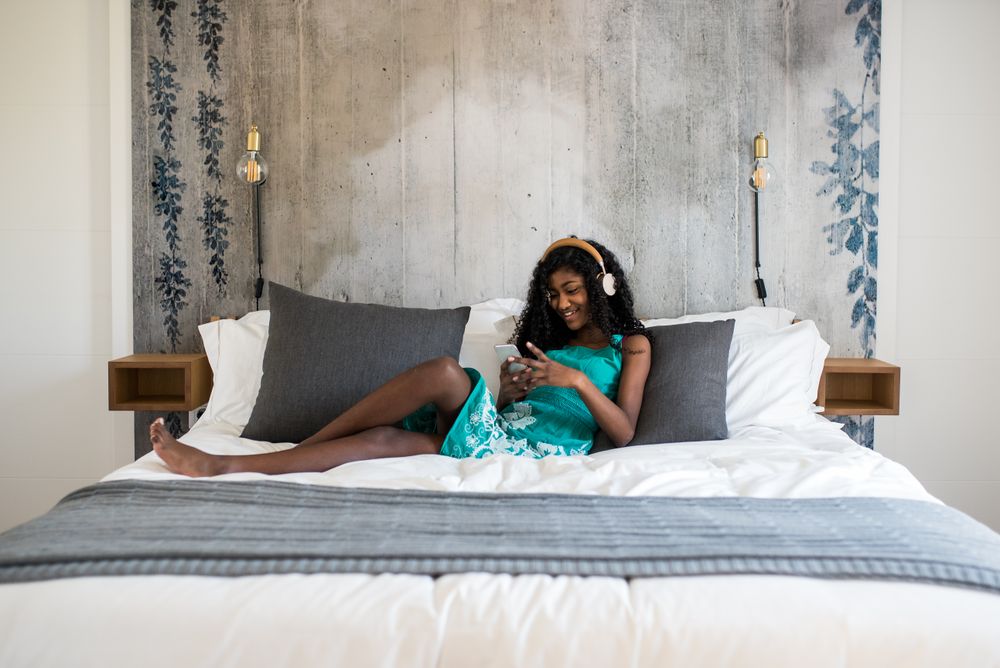 Black girl with headphones on bed
