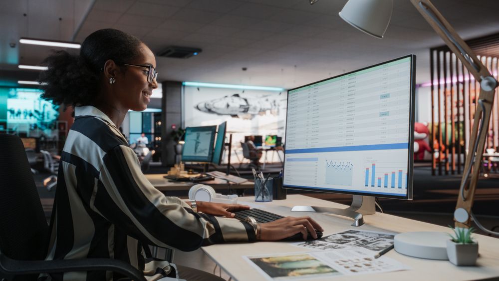 Female Manager Using Desktop Computer With Analytics Software wth Financial Reports.