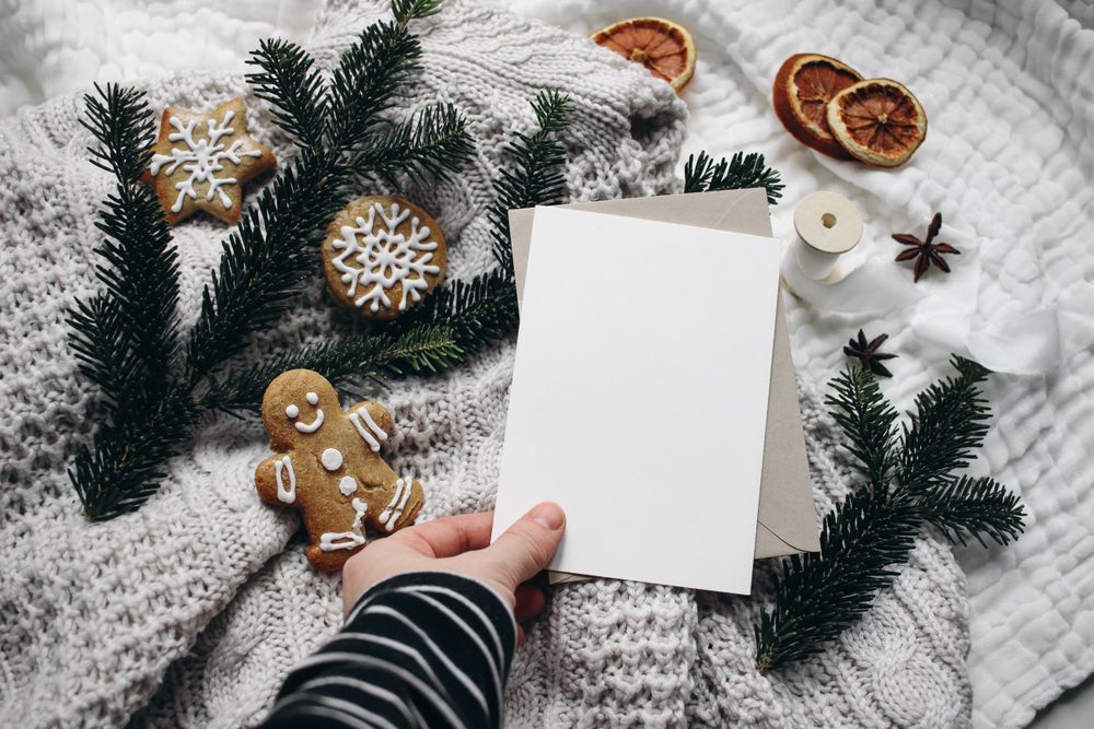 Christmas still life with hand holding blank card next to gingerbread cookie