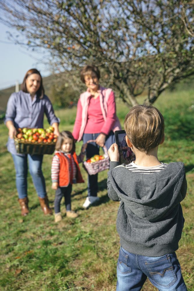 Boy taking photo of family with apples in basket