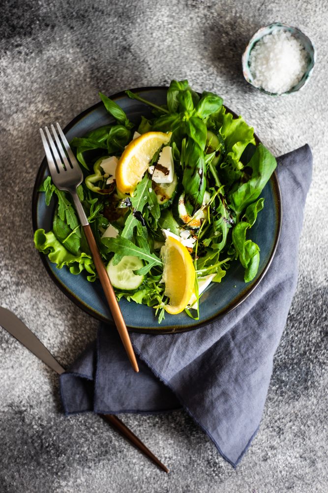 Top view of green salad with lemon slices