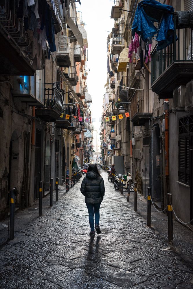 Anonymous female traveler in warm wear walking on narrow old street