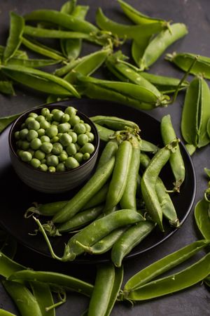 Fresh peas and pea pods on dark background