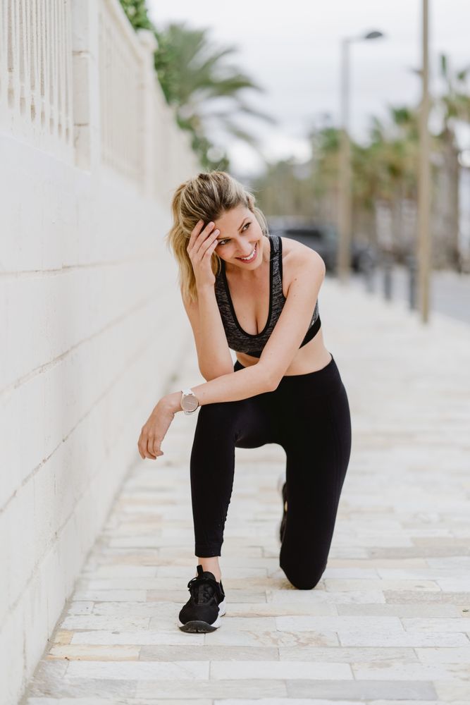 Satisfied sportswoman in active clothing smiling while exercising