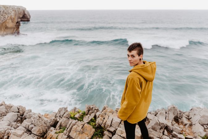Person in yellow hoodie on stony shore