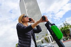 Woman talking on smartphone and riding electric scooter