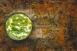Green vegetable cream soup with crackers and peas in a pan
