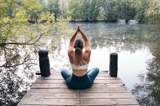 Woman in sportswear doing yoga in nature near a lake
